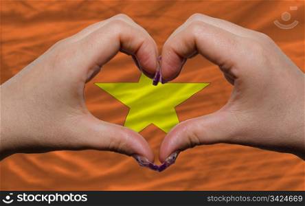 Gesture made by hands showing symbol of heart and love over national vietnam flag