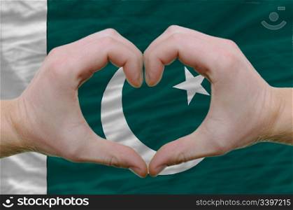 Gesture made by hands showing symbol of heart and love over pakistan flag