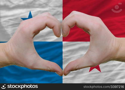 Gesture made by hands showing symbol of heart and love over panama flag