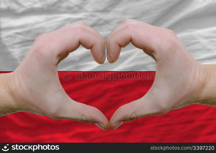 Gesture made by hands showing symbol of heart and love over poland flag