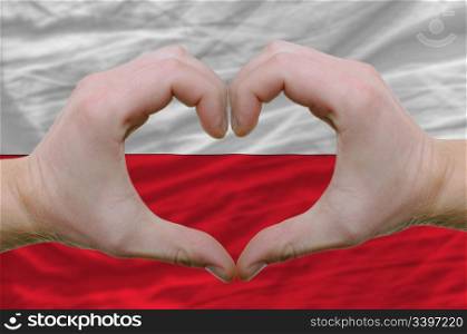 Gesture made by hands showing symbol of heart and love over poland flag