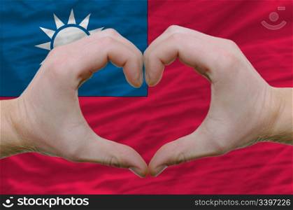 Gesture made by hands showing symbol of heart and love over taiwan flag