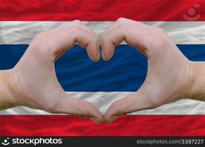 Gesture made by hands showing symbol of heart and love over thailand flag