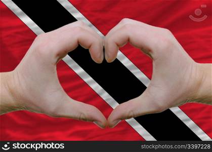 Gesture made by hands showing symbol of heart and love over trinidad and tobaog flag