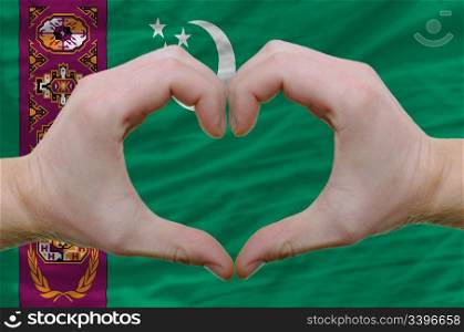 Gesture made by hands showing symbol of heart and love over turkmenistan flag