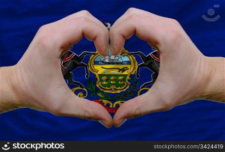 Gesture made by hands showing symbol of heart and love over us state flag of pennsylvania