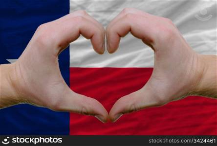 Gesture made by hands showing symbol of heart and love over us state flag of texas
