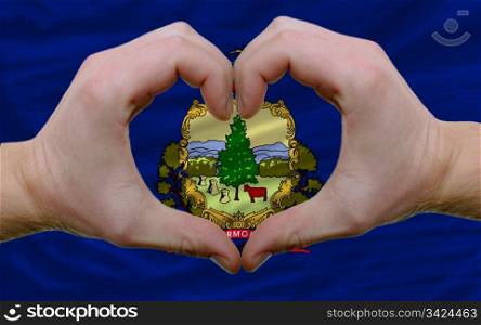 Gesture made by hands showing symbol of heart and love over us state flag of vermont