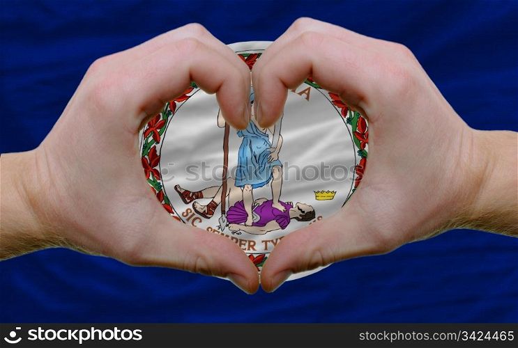 Gesture made by hands showing symbol of heart and love over us state flag of virginia