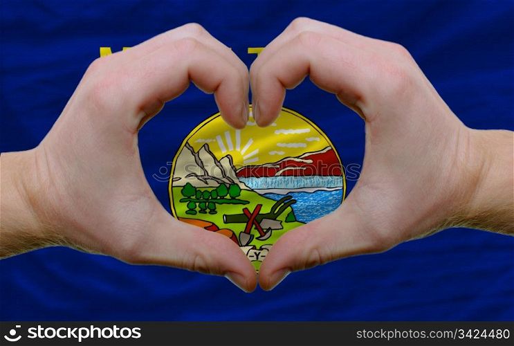 Gesture made by hands showing symbol of heart and love over us state flag of montana