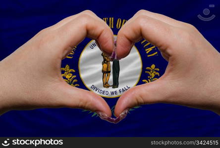 Gesture made by hands showing symbol of heart and love over us state flag of kentucky