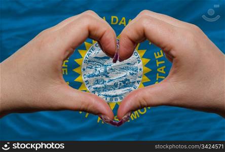 Gesture made by hands showing symbol of heart and love over us state flag of south dakota