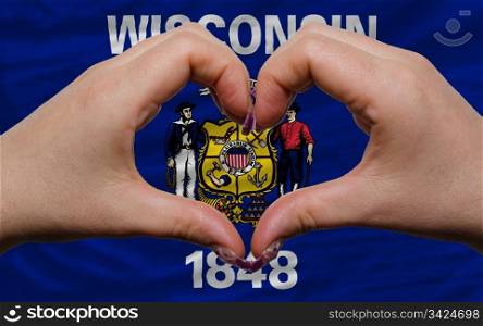 Gesture made by hands showing symbol of heart and love over us state flag of wisconsin