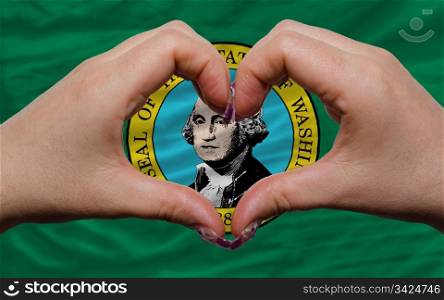 Gesture made by hands showing symbol of heart and love over us state flag of washington