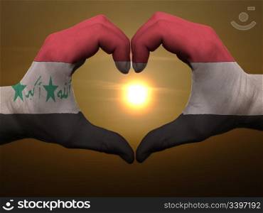 Gesture made by iraq flag colored hands showing symbol of heart and love during sunrise