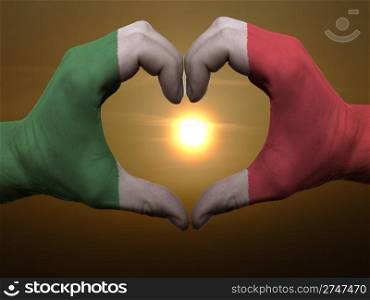 Gesture made by italy flag colored hands showing symbol of heart and love during sunrise