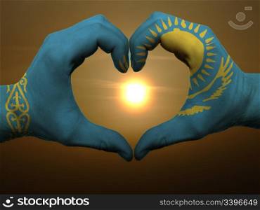 Gesture made by kazakstan flag colored hands showing symbol of heart and love during sunrise