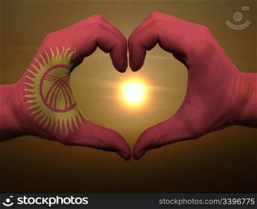 Gesture made by kyrghyzstan flag colored hands showing symbol of heart and love during sunrise