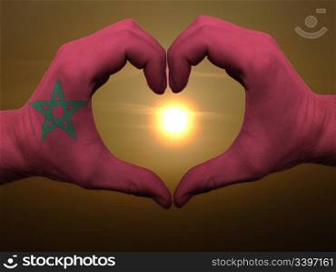 Gesture made by morocco flag colored hands showing symbol of heart and love during sunrise