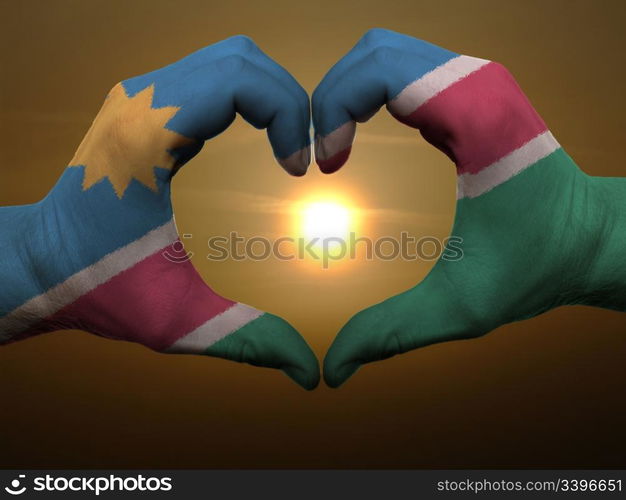 Gesture made by namibia flag colored hands showing symbol of heart and love during sunrise