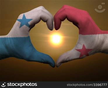 Gesture made by panama flag colored hands showing symbol of heart and love during sunrise