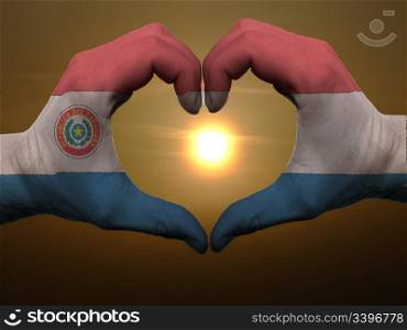 Gesture made by paraguay flag colored hands showing symbol of heart and love during sunrise