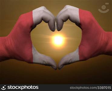 Gesture made by peru flag colored hands showing symbol of heart and love during sunrise