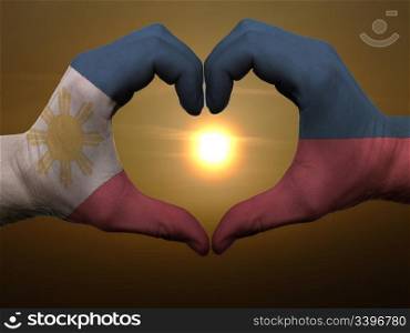 Gesture made by phillipines flag colored hands showing symbol of heart and love during sunrise