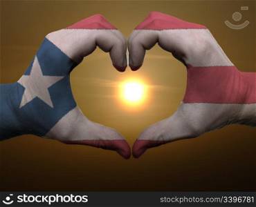 Gesture made by puertorico flag colored hands showing symbol of heart and love during sunrise