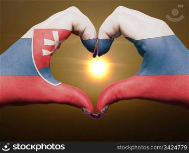Gesture made by slovakia flag colored hands showing symbol of heart and love during sunrise