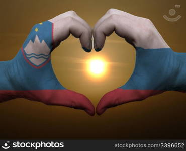 Gesture made by slovenia flag colored hands showing symbol of heart and love during sunrise