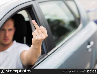 gesture, morals and people concept - close up of man driving car and showing middle finger hand sign