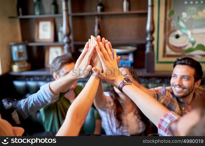 gesture, people and friendship concept - happy friends drinking beer and making high five at bar or pub. happy friends making high five at bar