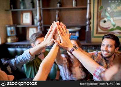 gesture, people and friendship concept - happy friends drinking beer and making high five at bar or pub. happy friends making high five at bar