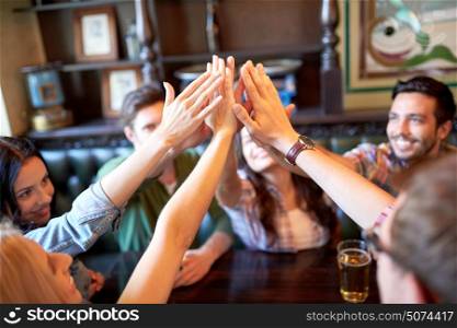 gesture, people and friendship concept - happy friends drinking beer and making high five at bar or pub. friends drinking beer and making high five at bar