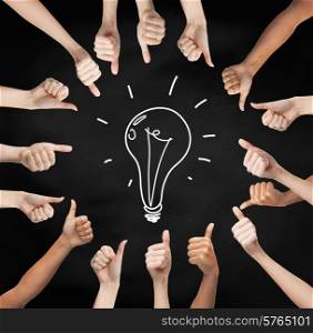 gesture, people, idea and development concept - human hands showing thumbs up in circle over black board background with drawing of lightning bulb in center