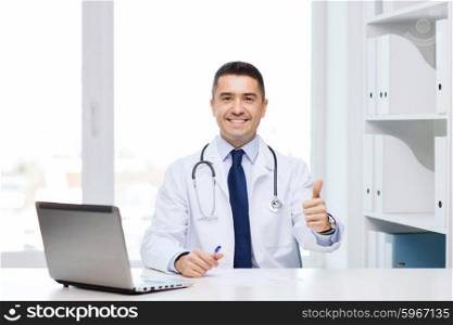gesture, profession, people and medicine concept - smiling male doctor in white coat showing thumbs up in medical office