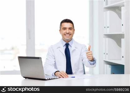 gesture, profession, people and medicine concept - smiling male doctor in white coat showing thumbs up in medical office