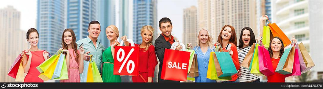 gesture, shopping and people concept - group of happy people with sale sign showing thumbs up