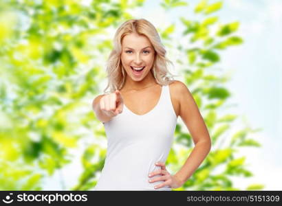 gesture, summer and people concept - happy smiling beautiful young woman in white top and jeans with blonde hair over green natural background. happy smiling young woman with blonde hair