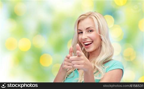 gesture, summer and people concept - happy smiling young woman or teenage girl pointing finger to you over green lights background