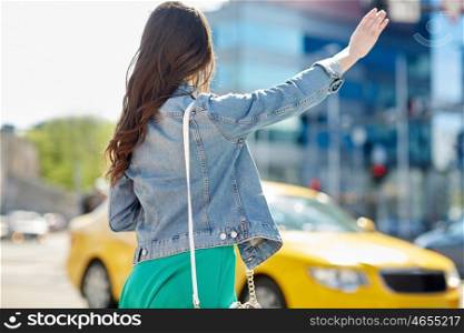 gesture, transportation, travel, tourism and people concept - young woman or teenage girl catching taxi on city street or hitch-hiking