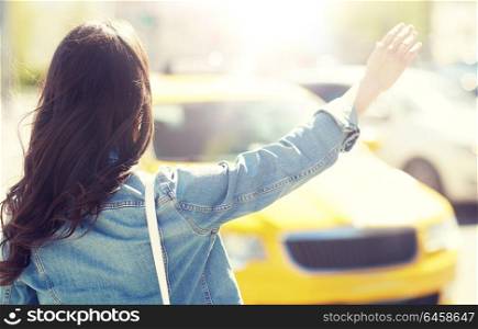 gesture, transportation, travel, tourism and people concept - young woman or teenage girl catching taxi on city street or hitch-hiking. young woman or girl catching taxi on city street