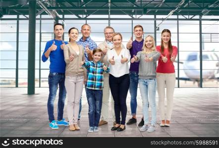 gesture, travel, tourism and people concept - big happy family showing thumbs up over airport terminal background