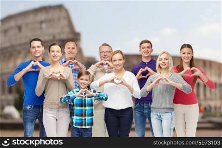 gesture, travel, tourism and people concept - happy family showing heart shape hand sign over coliseum background