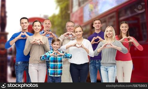 gesture, travel, tourism and people concept - happy family showing heart shape hand sign over london city street background