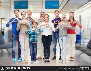 gesture, travel, tourism and people concept - happy family showing heart shape hand sign over airport waiting room background