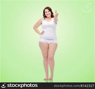 gesture, weight loss and people concept - smiling young plus size woman in underwear showing thumbs up over green natural background