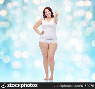 gesture, weight loss and people concept - smiling young plus size woman in underwear showing thumbs up background over blue holidays lights background