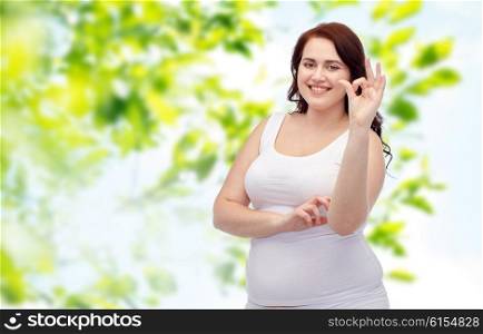 gesture, weight loss and people concept - smiling young plus size woman in underwear showing ok hand sign over green natural background